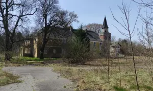 Opuszczony pałac w Torzymiu, z charakterystyczną wieżą, otoczony dziką roślinnością.
