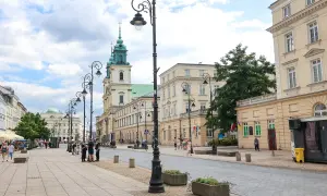 Spacer po Krakowskim Przedmieściu w Warszawie, z zabytkowymi kamienicami i kościołem w tle.
