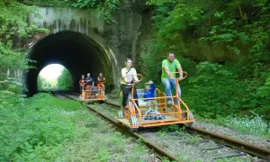 Rodzina na drezynach w Bieszczadach, przejeżdża obok tunelu w otoczeniu zieleni.