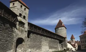 Kamienne mury obronne z drewnianymi gankami i wieżami, przypominające średniowieczne Inflanty. Co to za miejsce?