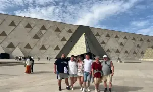 Rodzina pozuje przed nowoczesnym, geometrycznym budynkiem – nowym muzeum w Egipcie.
