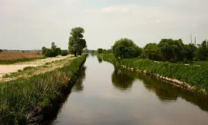 Prosta, spokojna rzeka Ner płynie przez zielone łąki i pola.