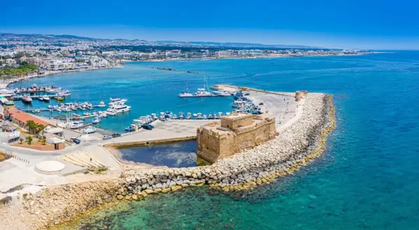 Zamek w Paphos, Cypr, nad turkusowym morzem. W tle port z łodziami i miasto. Idealne miejsce na wakacje, blisko lotniska.
