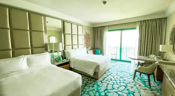 Pokój hotelowy z dwoma łóżkami i dywanem w kolorze mokrej wody.