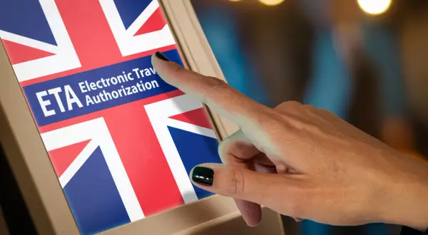 Dłoń naciska ekran z flagą Wielkiej Brytanii i napisem "ETA Electronic Travel Authorization". To krok do uzyskania wizy do Londynu.