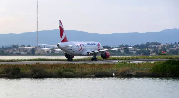 Samolot Czech Airlines kołuje na pasie startowym lotniska na Korfu. W tle góry i zabudowania.