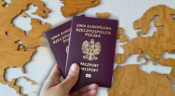Dwa polskie paszporty w dłoni na tle mapy Europy. Zastanawiasz się, ile kosztuje paszport?