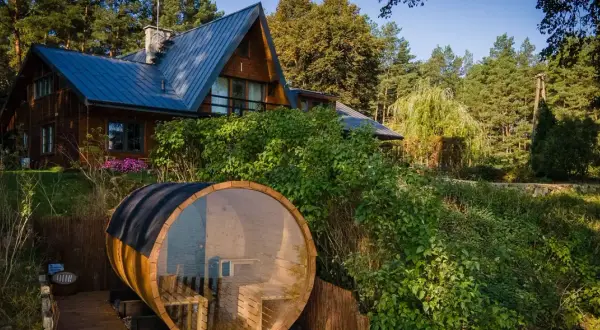 Drewniany domek letniskowy nad jeziorem z beczką sauny. Idealne miejsce na relaks w otoczeniu natury. Tanie domki letniskowe nad jeziorem czekają!