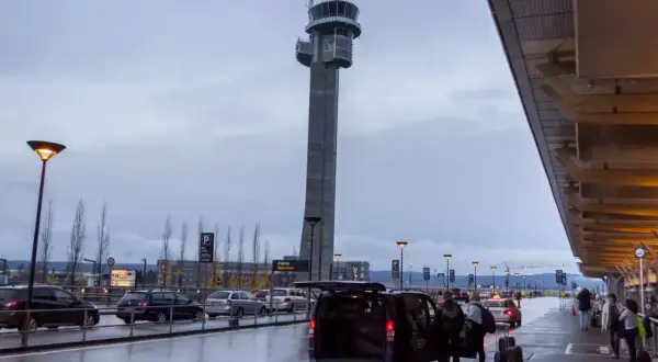 Wieża kontrolna na oslo lotnisko, deszczowa pogoda, ludzie z bagażami wsiadają do vana.