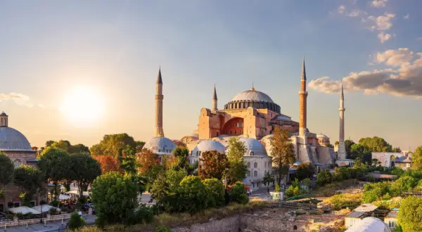 Majestatyczny meczet Hagia Sophia w Stambule, z minaretami i kopułami, oświetlony zachodzącym słońcem.