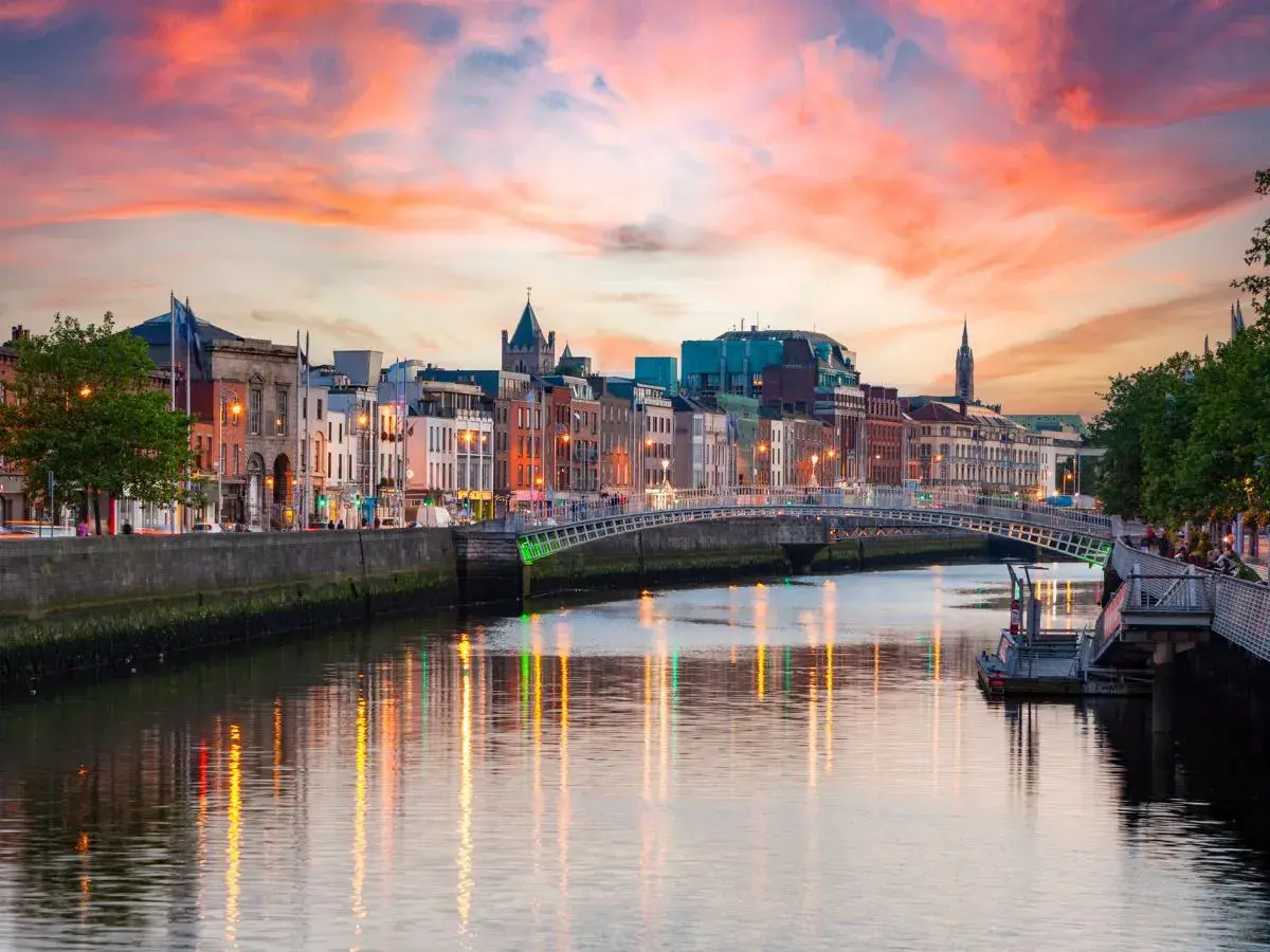 Zachód słońca nad rzeką Liffey, gdzie jest Dublin. Widać most Ha'penny i kolorowe kamienice.
