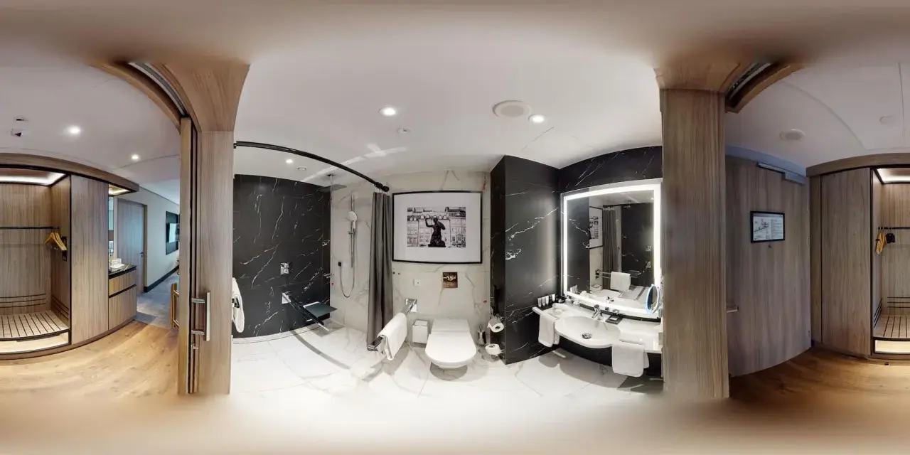 Nowoczesna łazienka w pokoju hotelowym Radisson Collection Hotel Warsaw z czarnymi, marmurowymi ścianami, prysznicem, toaletą i umywalką.