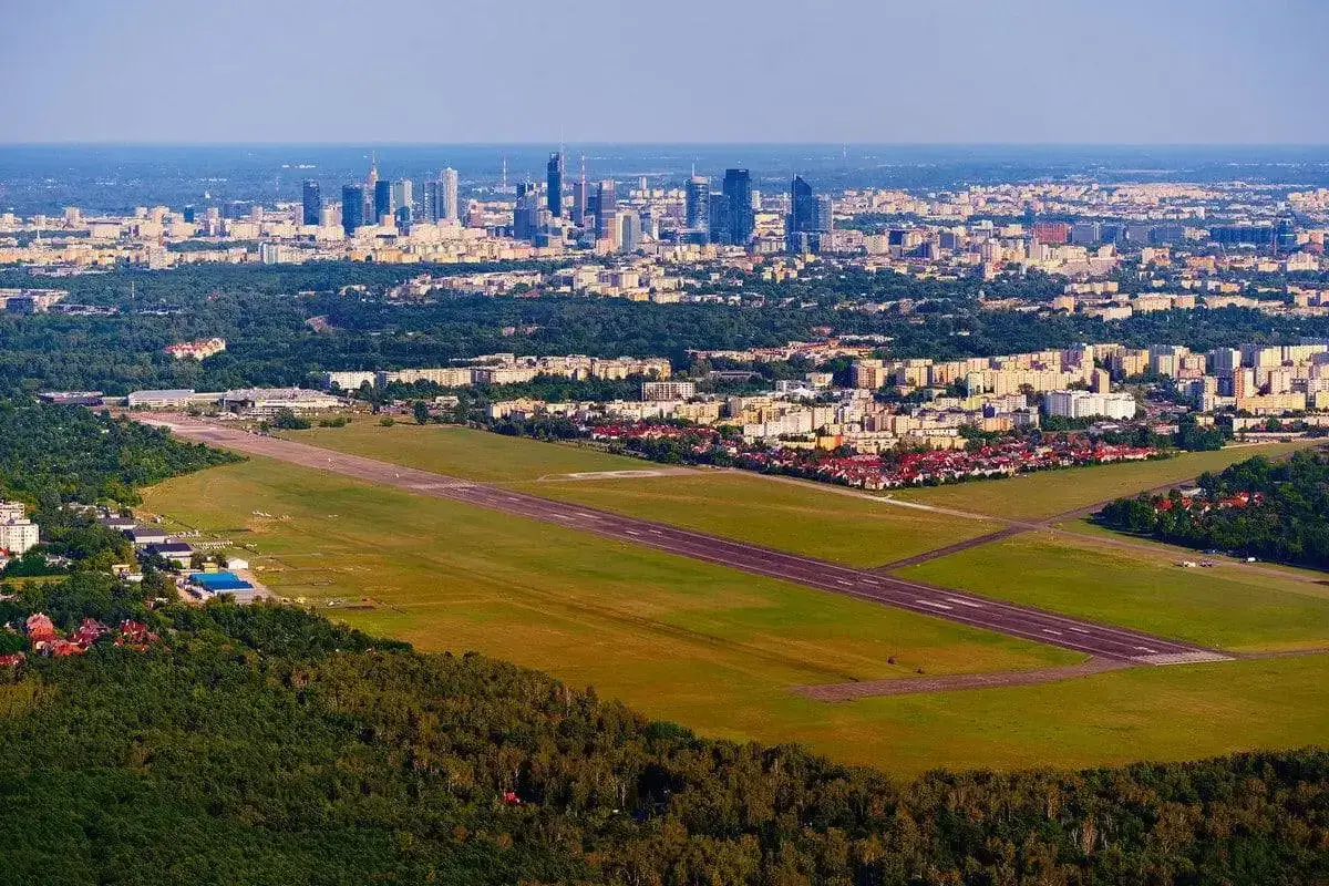 Lotnisko Bemowo z pasem startowym i panoramą Warszawy w tle.
