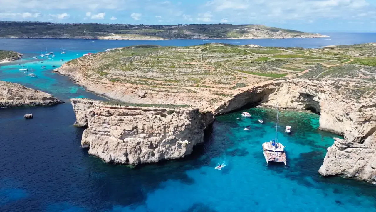Malta wakacje: Błękitna Laguna z łodziami i klifami, idealne miejsce na relaks i podziwianie krajobrazów.