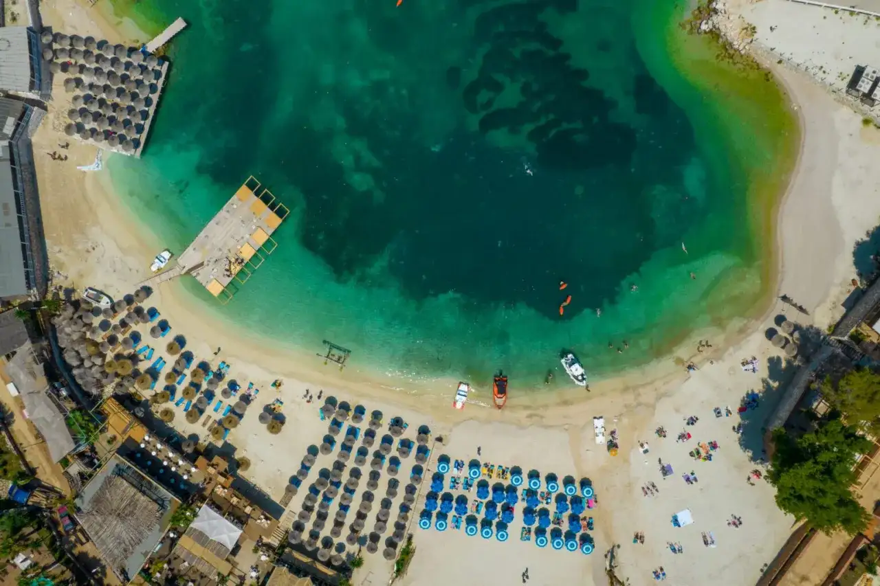 Rajska plaża w Albanii, idealne miejsce na wakacje. Turkusowa woda, złoty piasek i mnóstwo leżaków pod parasolami.