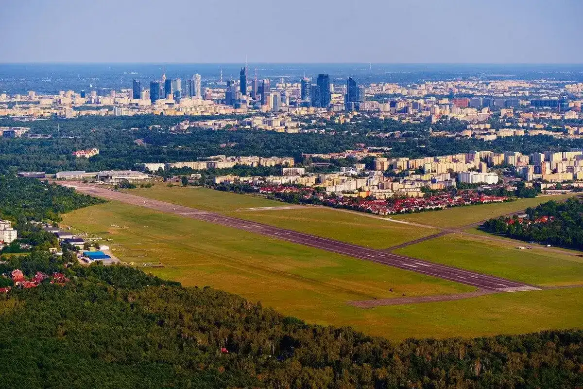 Lotnisko Bemowo z pasem startowym i panoramą Warszawy w tle.