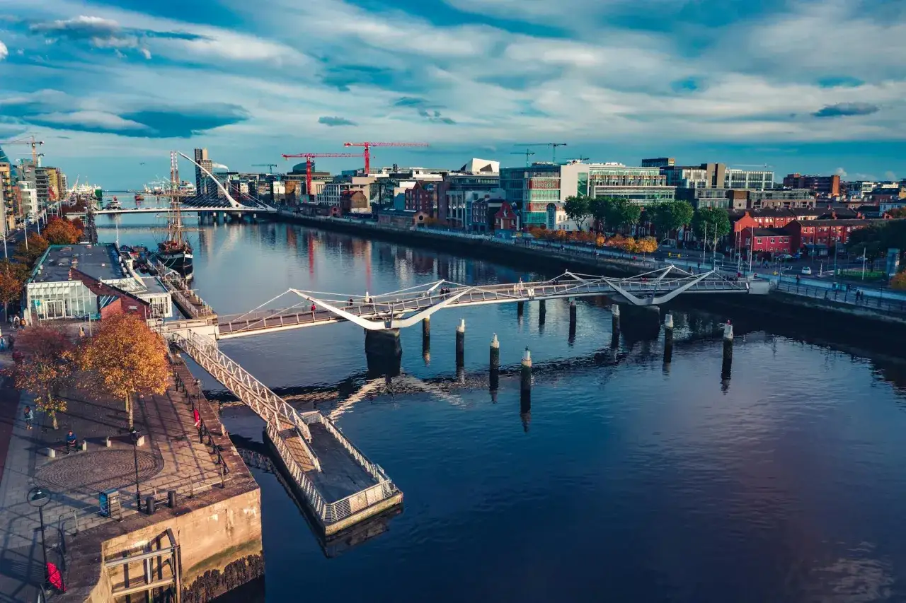 Widok na rzekę Liffey i nowoczesne mosty, gdzie jest Dublin. W tle budynki i dźwigi.