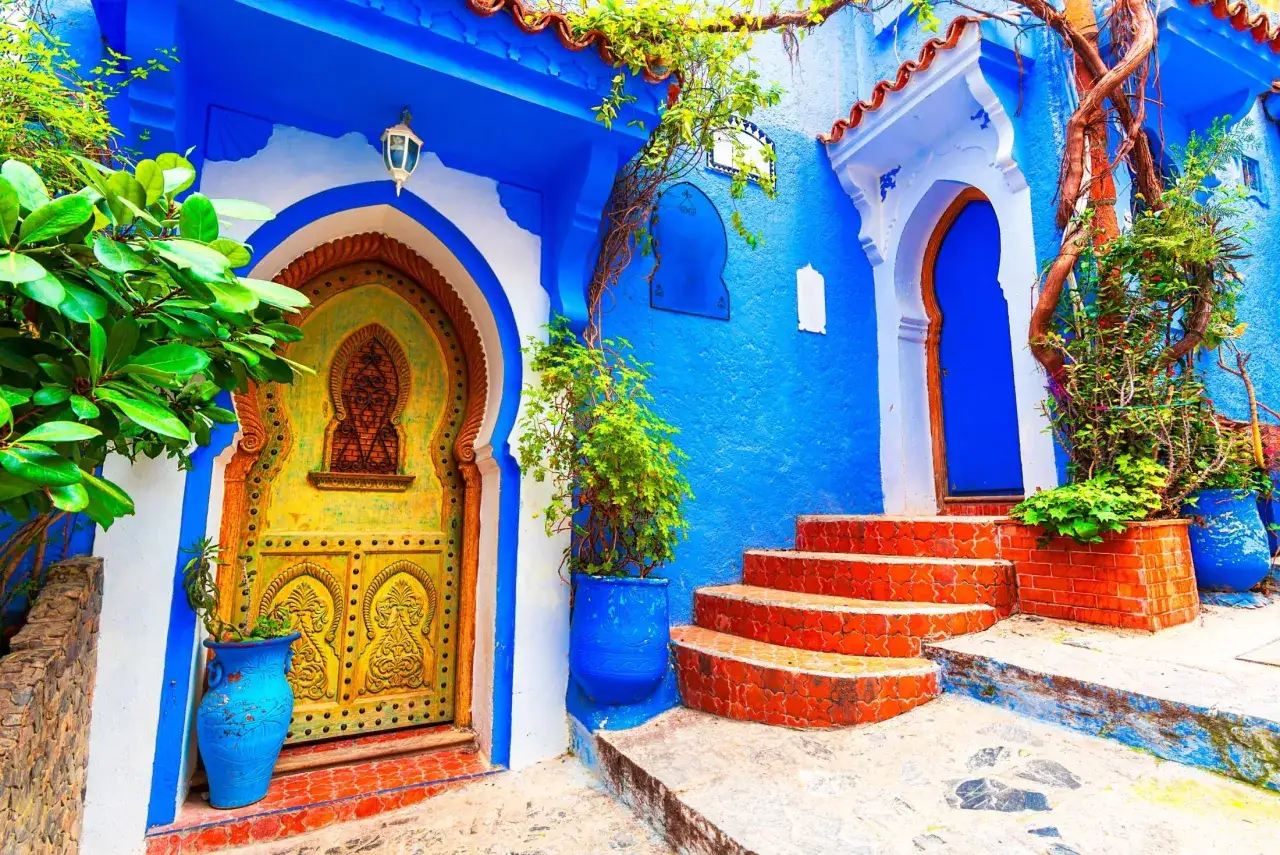 Niebieskie miasto Maroko, Chefchaouen, zachwyca kolorami. Żółte drzwi, niebieskie ściany i czerwone schody tworzą magiczny zakątek.