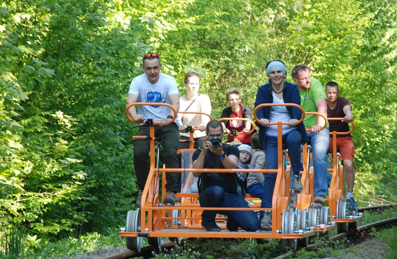 Rodzina na drezynach w Bieszczadach, ciesząca się słońcem i zielenią.