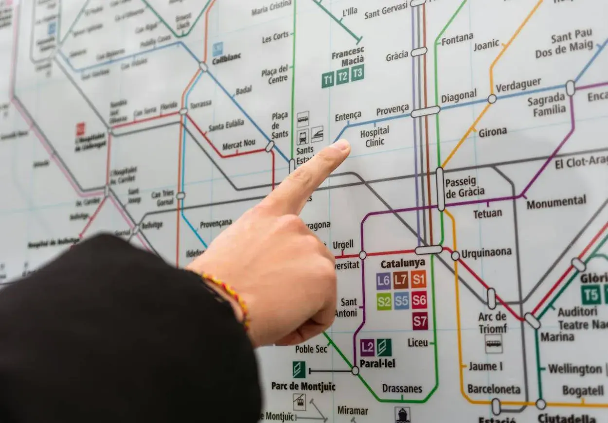 Palec wskazuje na mapę metra w Barcelonie, szukając połączenia z lotniska Barcelona El Prat.