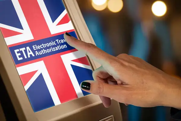 Palec dotyka ekranu z flagą Wielkiej Brytanii i napisem "ETA Electronic Travel Authorization". Zastanawiasz się, ile kosztuje ETA do UK?